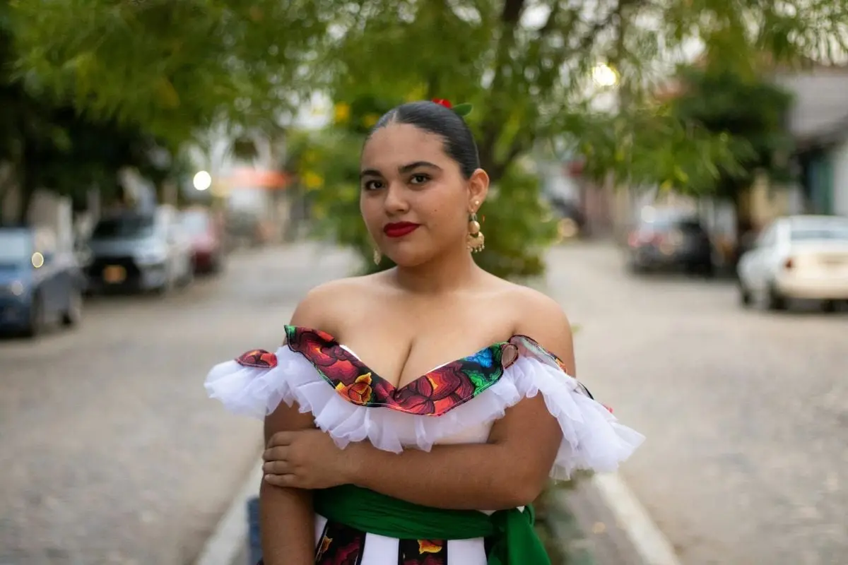 Young woman in traditional attire posing confidently outdoors on a cobblestone street.
