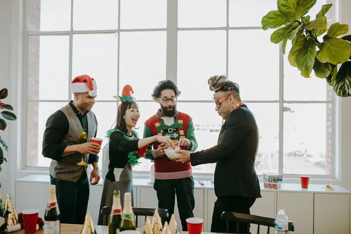 Diverse group of friends celebrating Christmas indoors with drinks and snacks.