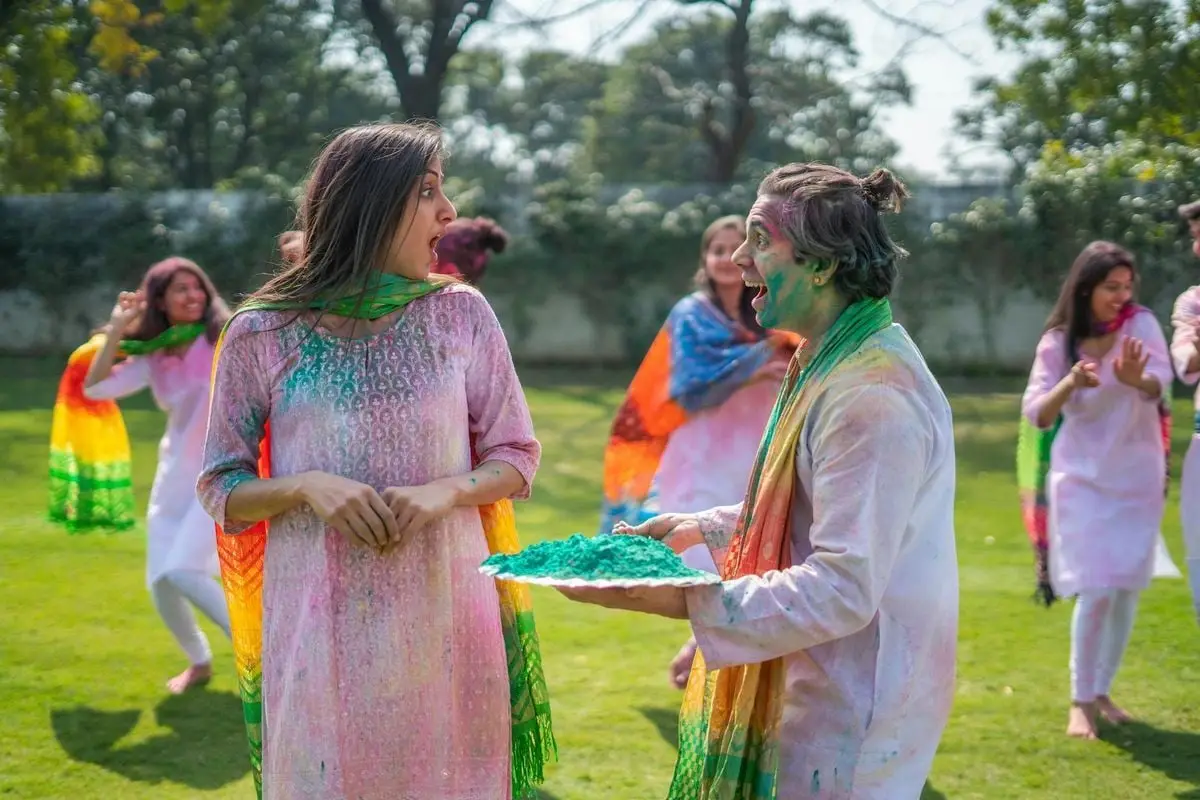 Lively outdoor Holi festival scene with vibrant colors and joyful interactions among participants.