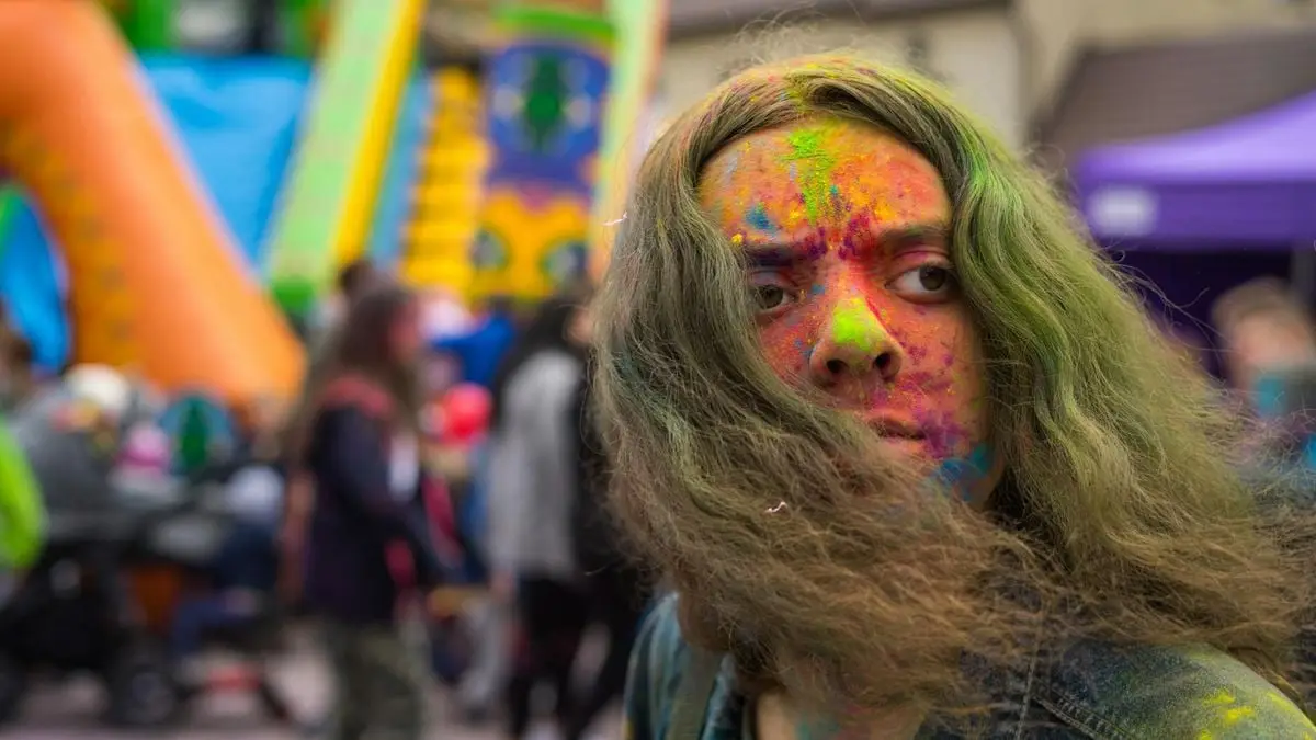 Vibrant festival scene with a person covered in colorful paint, capturing the joy and spirit of celebration.