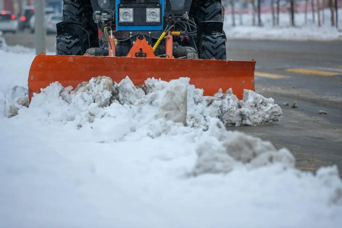 A snowplow clearing snow from a city street after a heavy winter snowstorm.