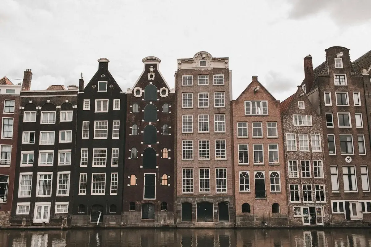 Scenic view of historic canal houses in Amsterdam, reflecting Dutch architecture by the water.