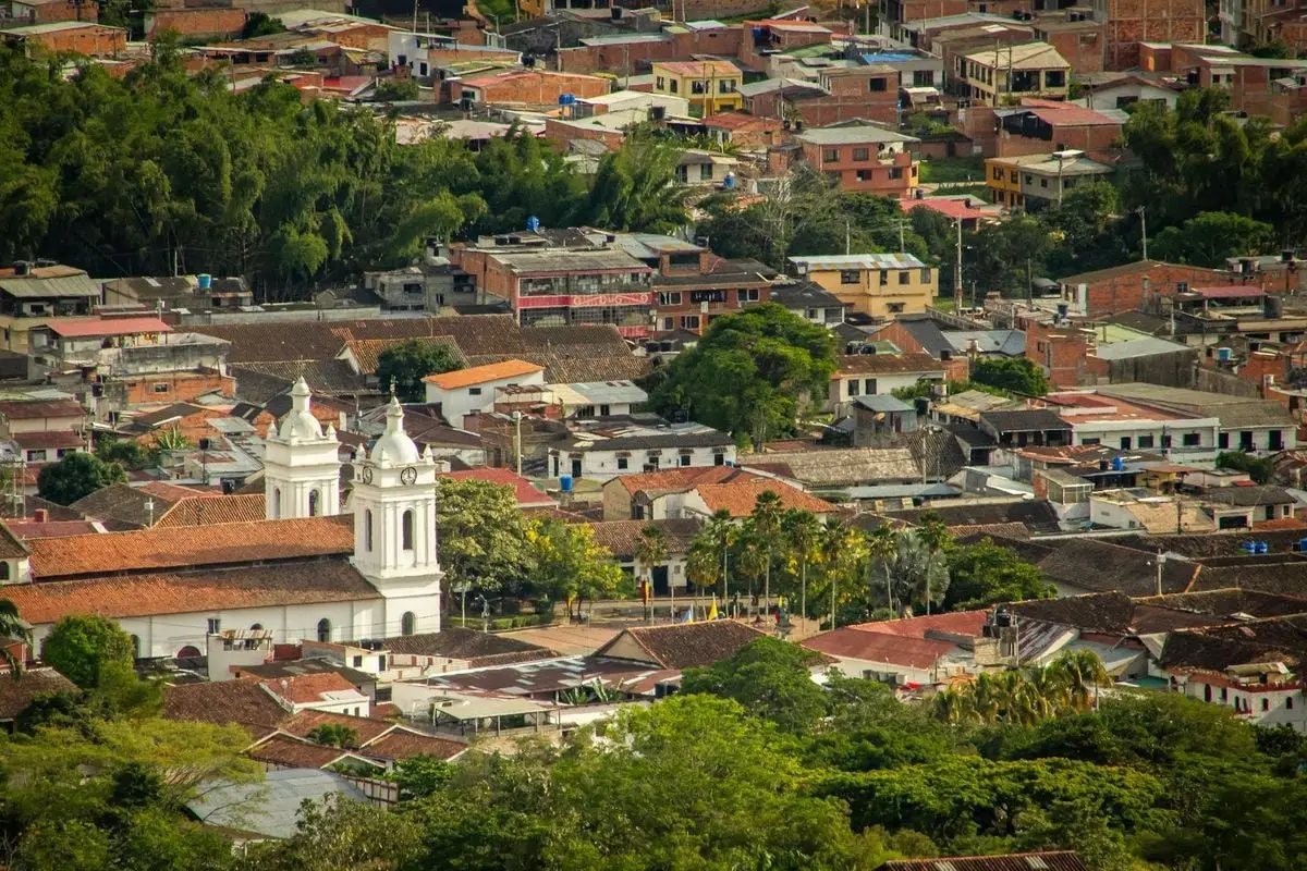 Aerial shot of a picturesque colonial town with a prominent church surrounded by lush greenery.