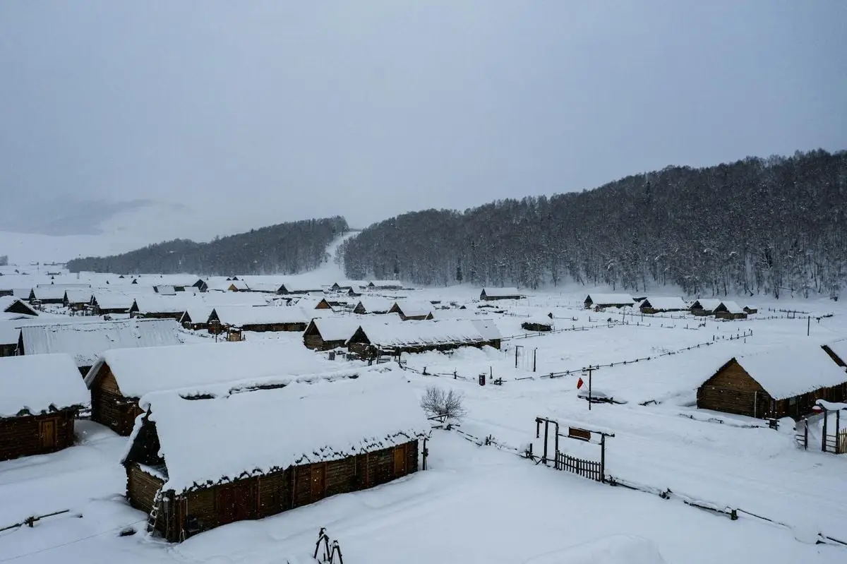 Snow-covered wooden houses in Altay Prefecture, Xinjiang during winter snowfall.