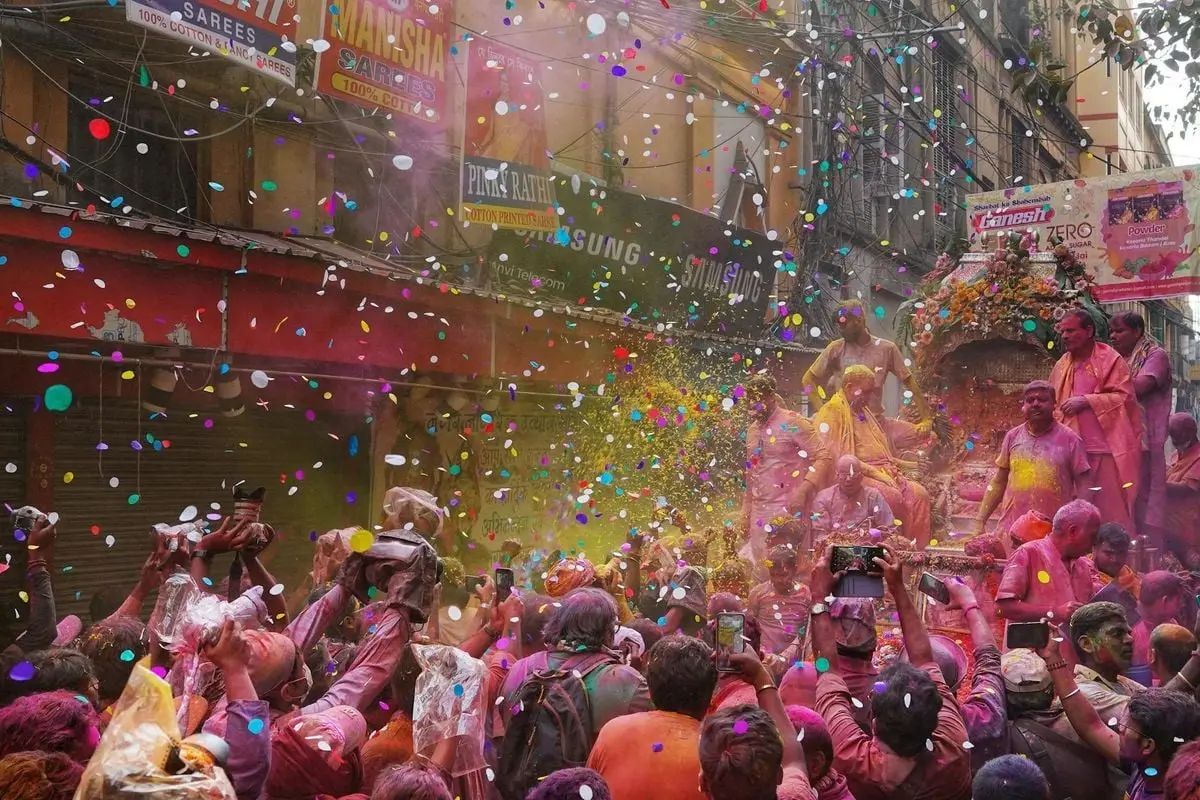 Colorful Holi festival celebration with joyful crowd in Kolkata, India.