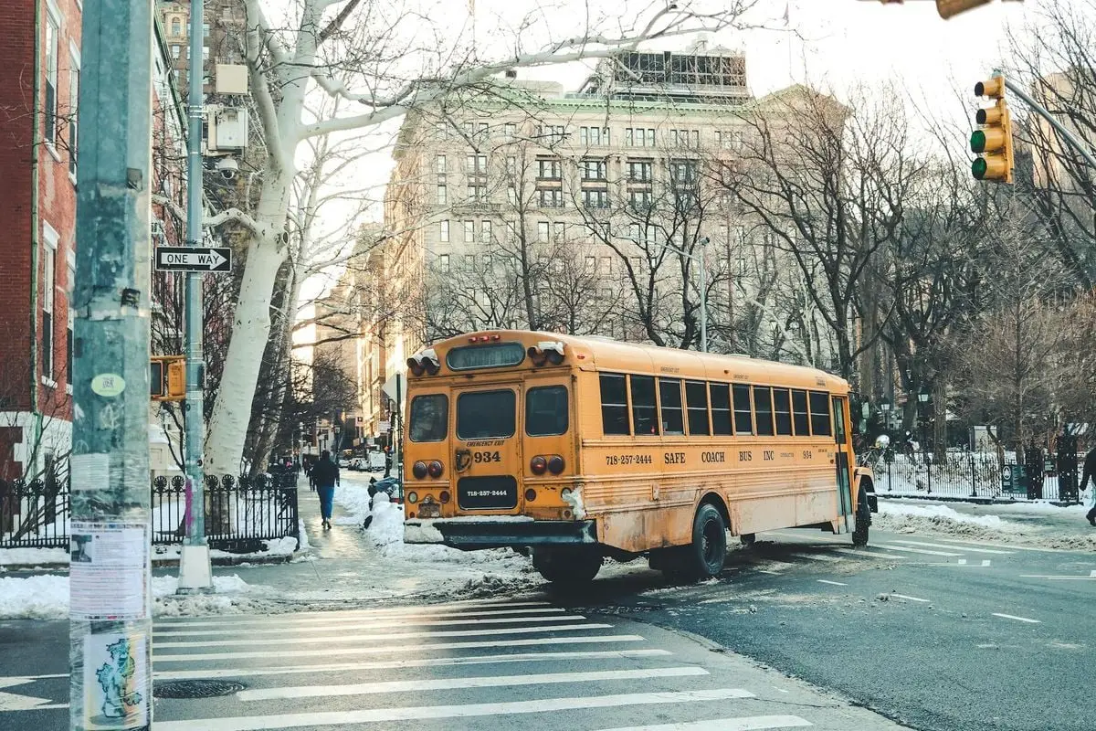 A classic yellow school bus navigating a snowy city street in winter, Washington, DC.