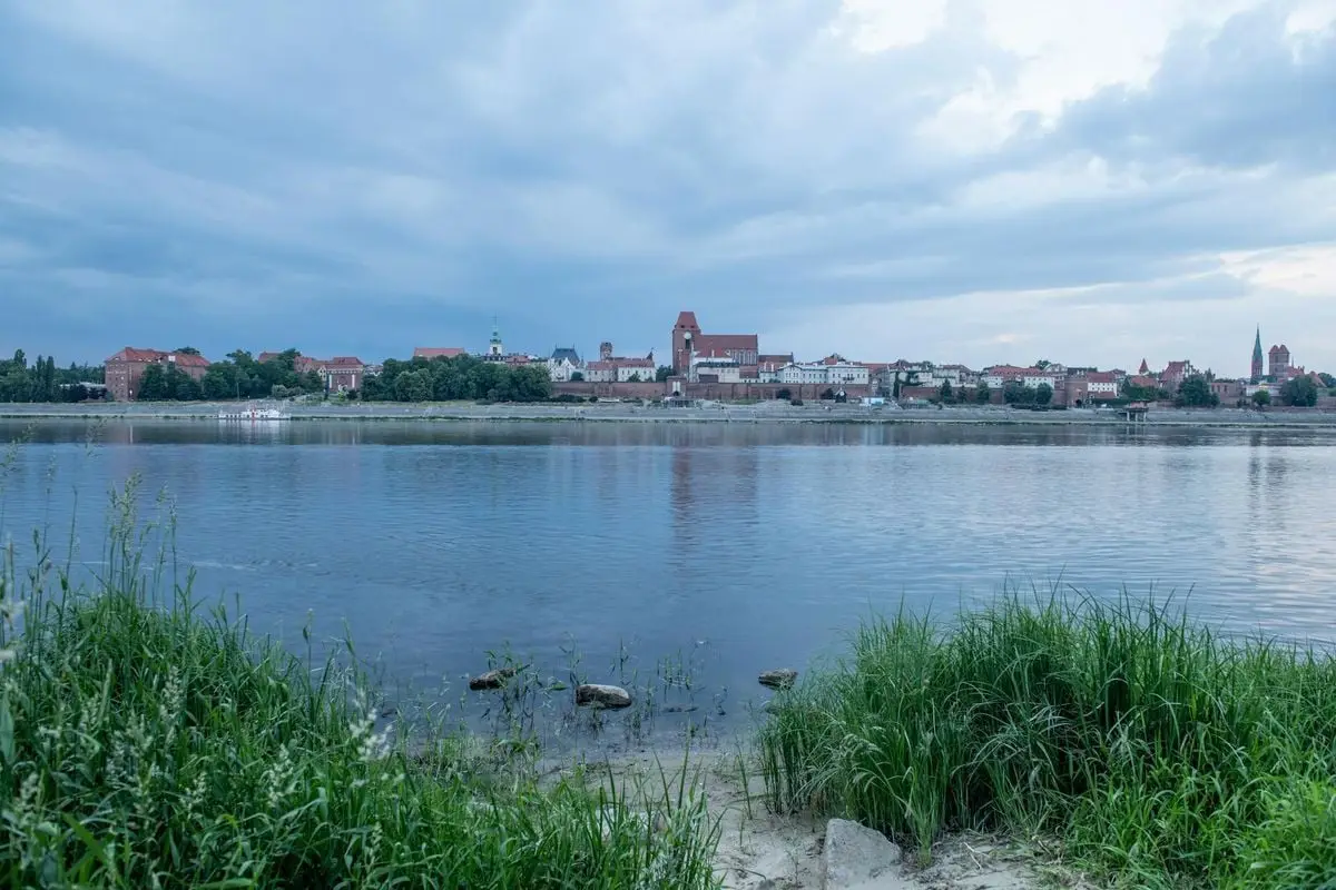Breathtaking view of Toruń's historic skyline across the calm Vistula River.