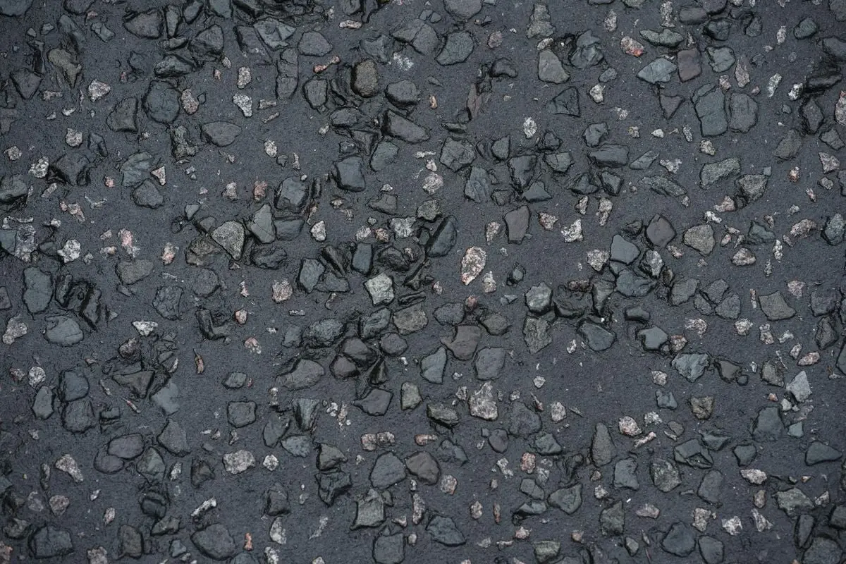 Top view of rough gray asphalt wet pavement of urban street on rainy day