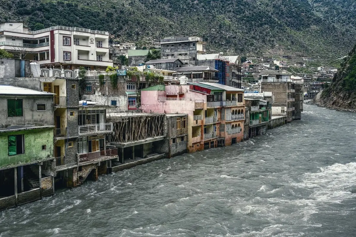 Vibrant houses along the river in a scenic mountain town, showcasing urban architecture.