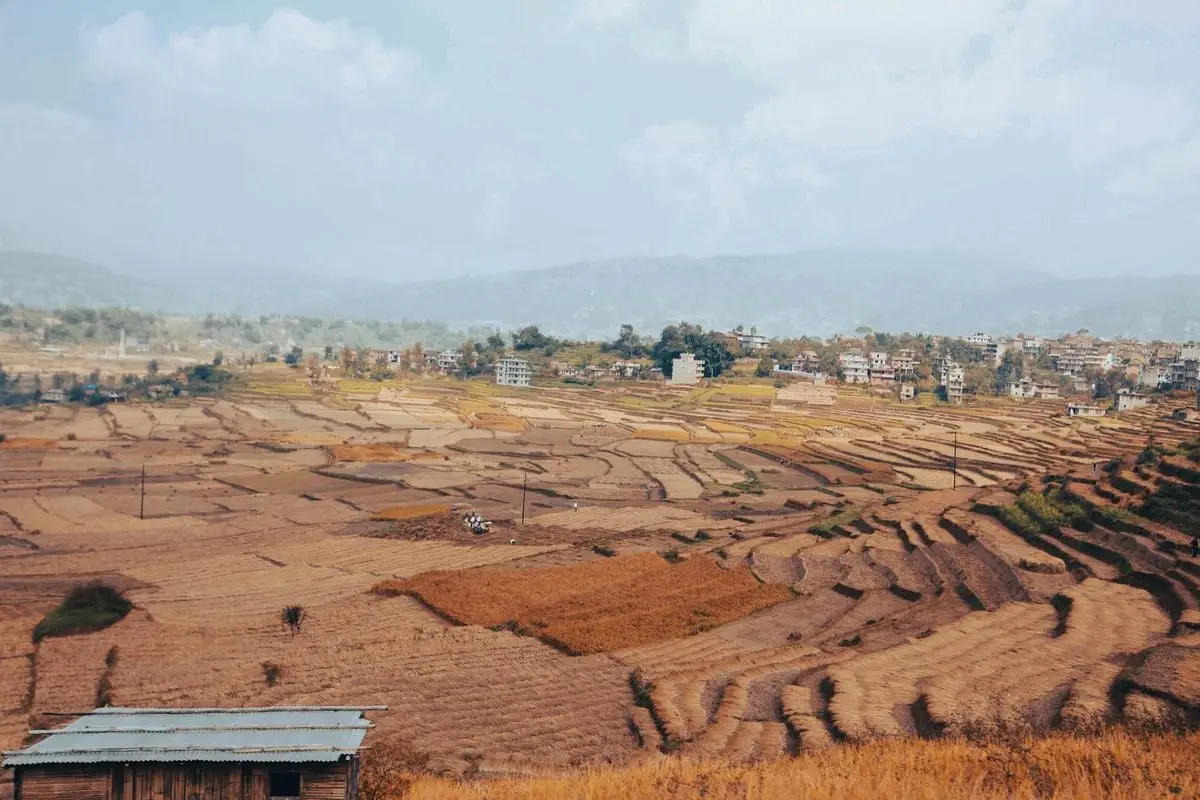 A stunning aerial view of terraced fields and a rural town under a cloudy sky.