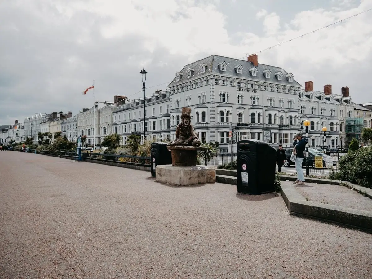 Explore the charming Llandudno promenade featuring the iconic Mad Hatter sculpture and historic architecture.