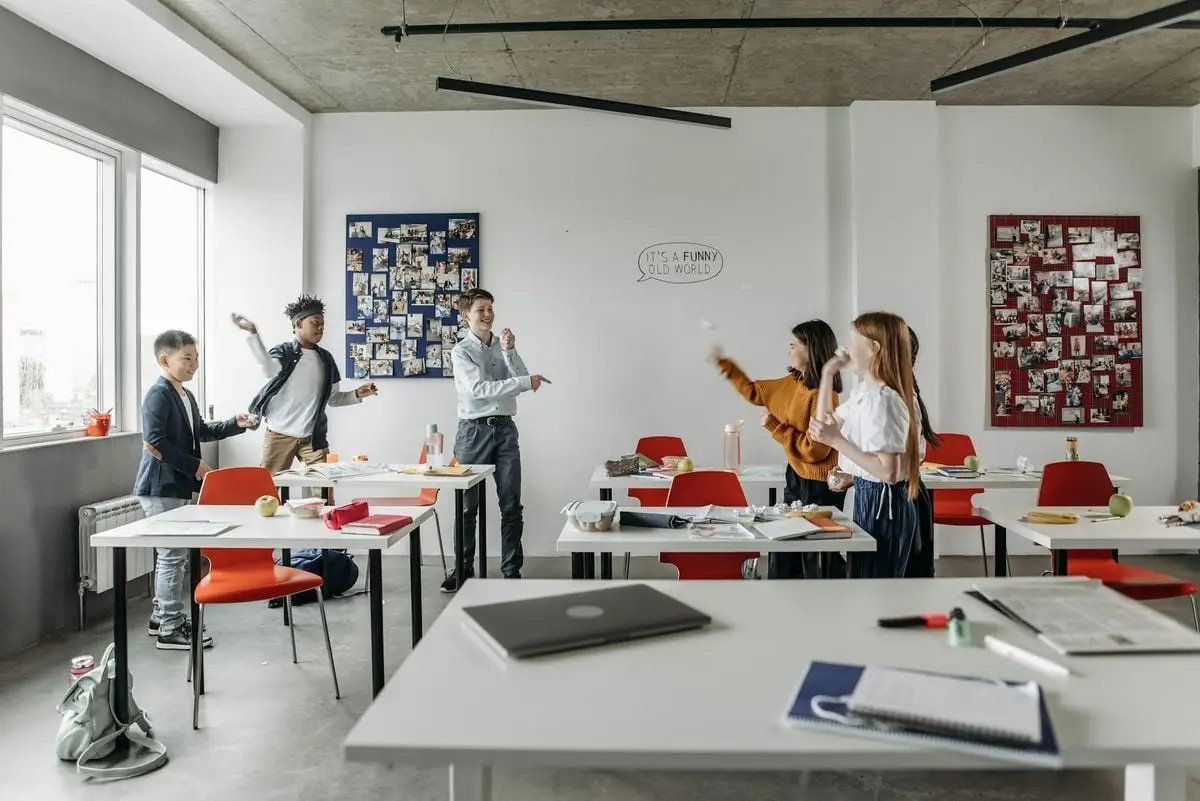 A group of diverse children playfully interacting in a school classroom during break time.