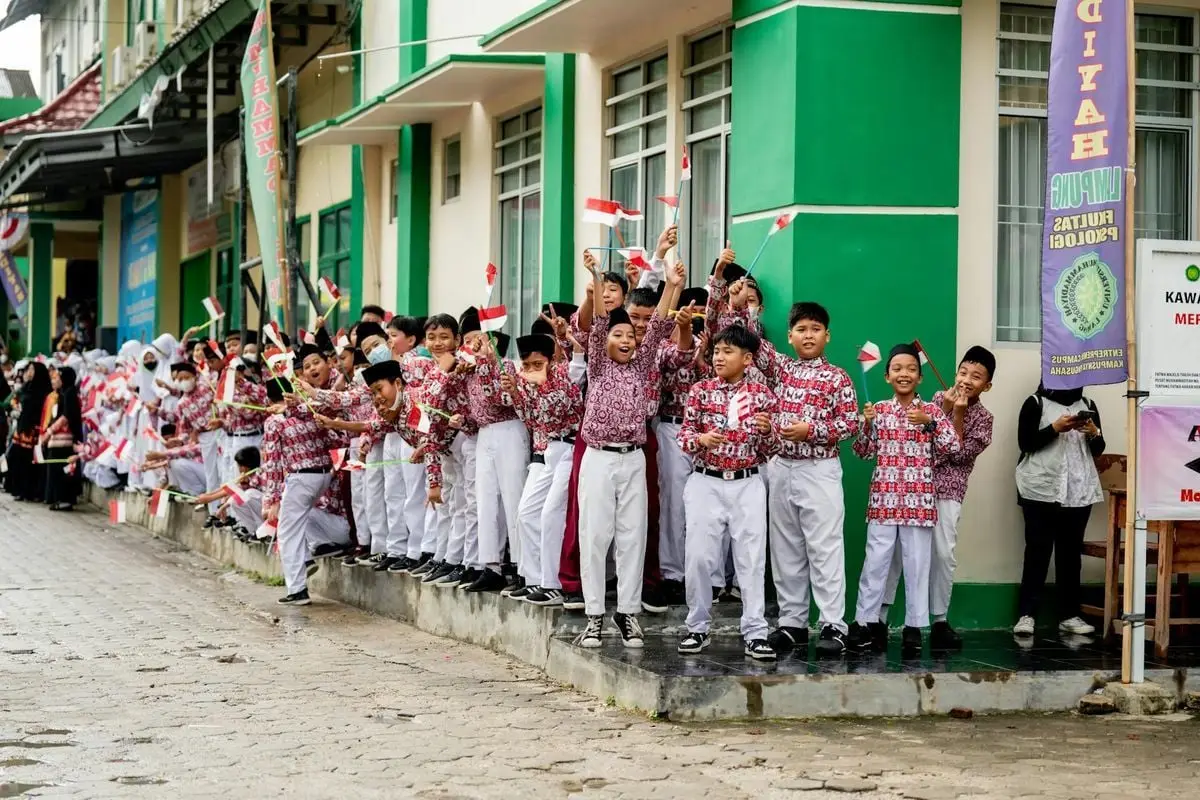 Joyful Indonesian children in uniforms waving flags during a celebration in Krui, Lampung.