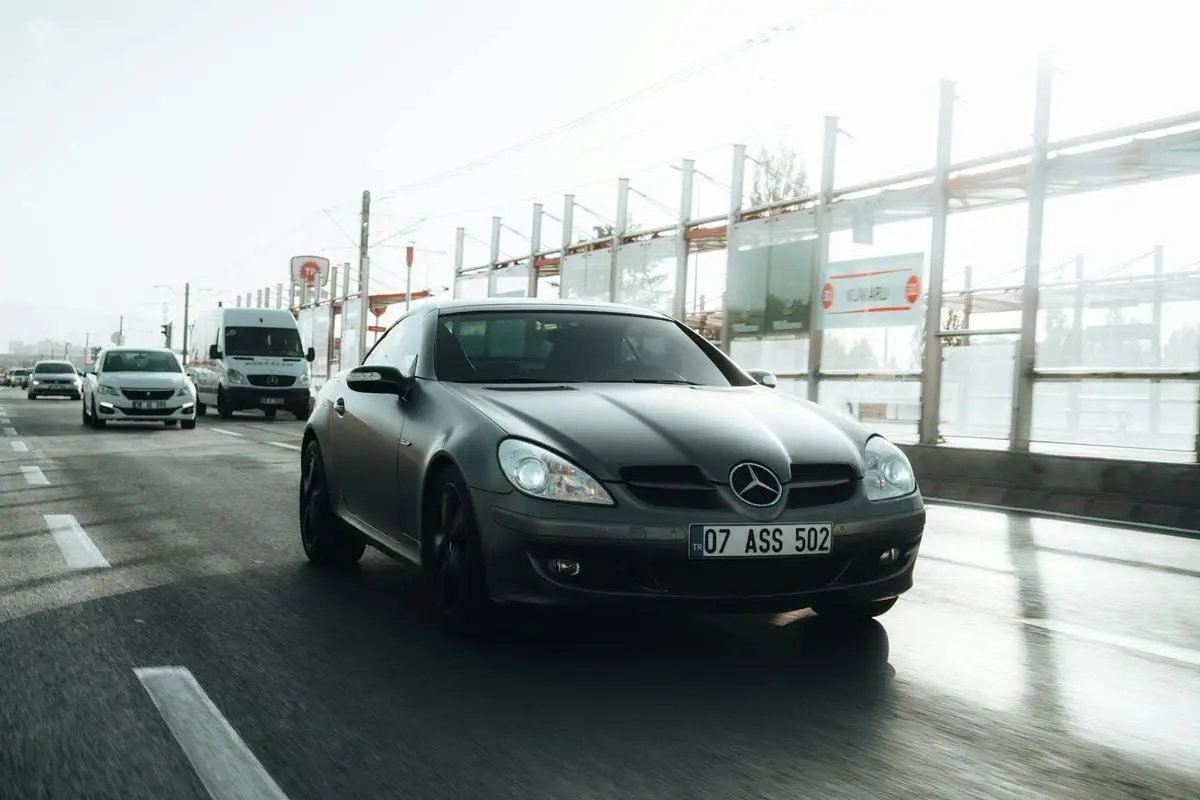 A sleek black Mercedes Benz cruising on a busy city road during the day.