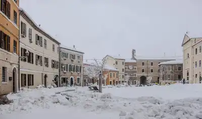 Picturesque snowy European town square with historic buildings during winter.