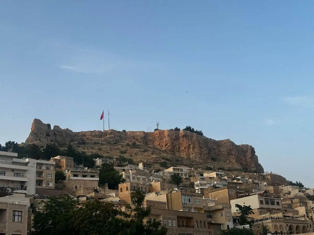 Scenic view of Mardin's ancient city and castle under clear blue sky.