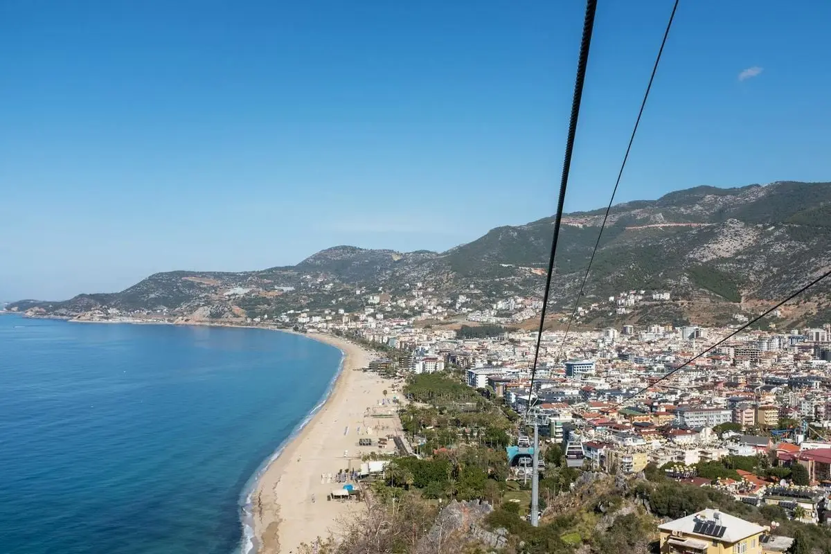 Stunning aerial view of Alanya's coastline with beach, town, and mountains.