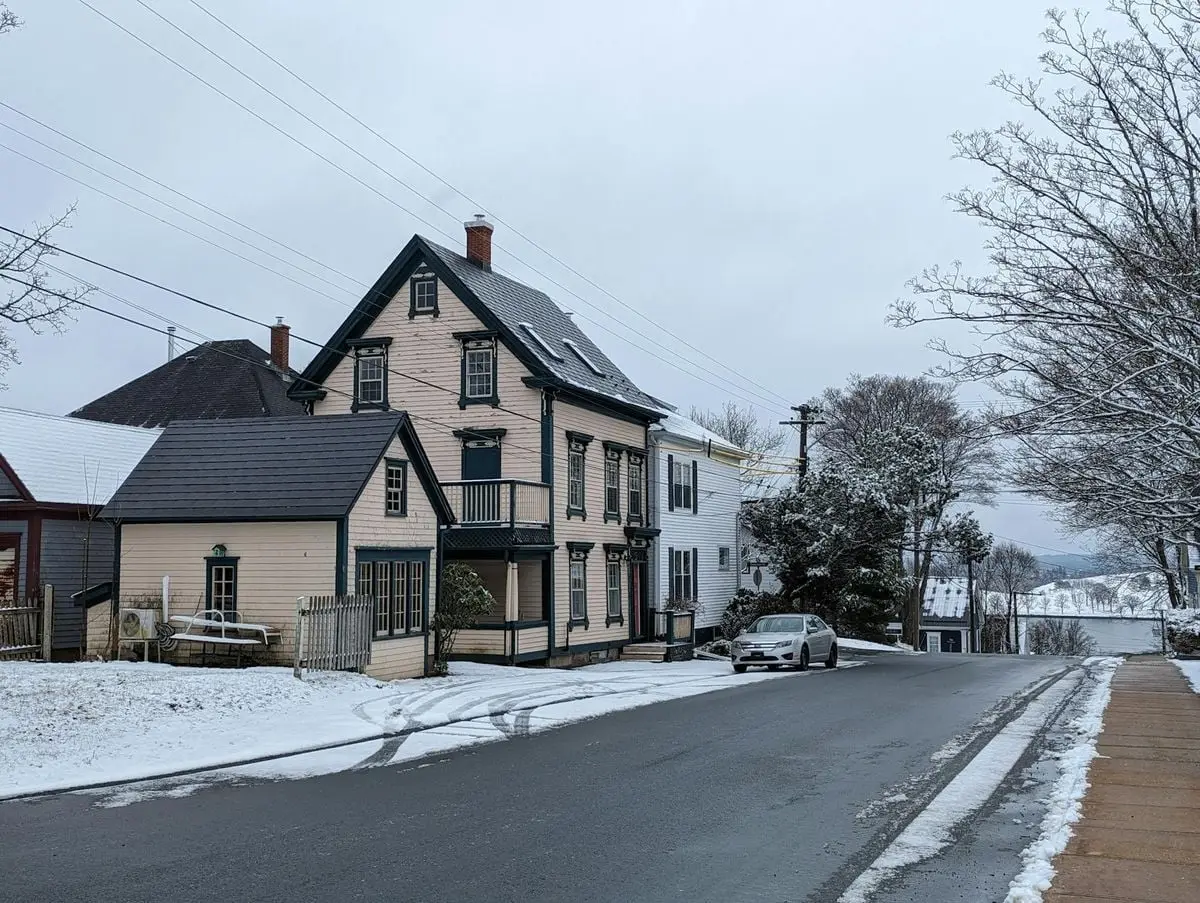 Charming snow-covered street in Lunenburg, Nova Scotia with historic architecture.