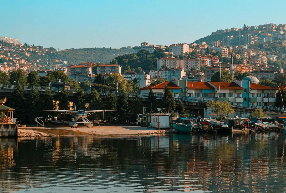 Explore İzmit's beautiful waterfront featuring a docked hydroplane against lush hills.