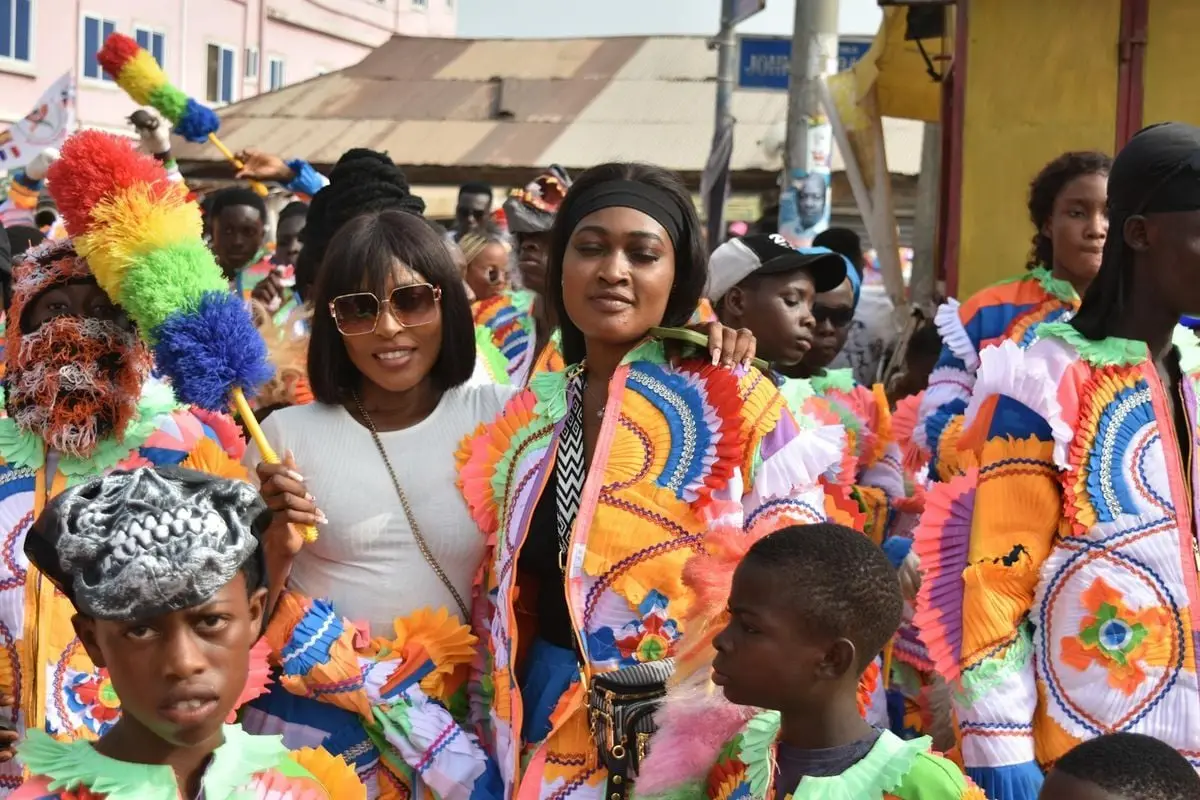A lively street festival with people in colorful traditional costumes celebrating joyously.