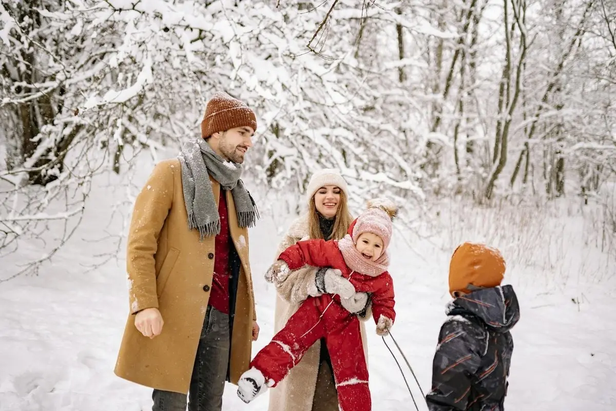 Happy family enjoying a snowy day in the winter woods, smiling and playing together.