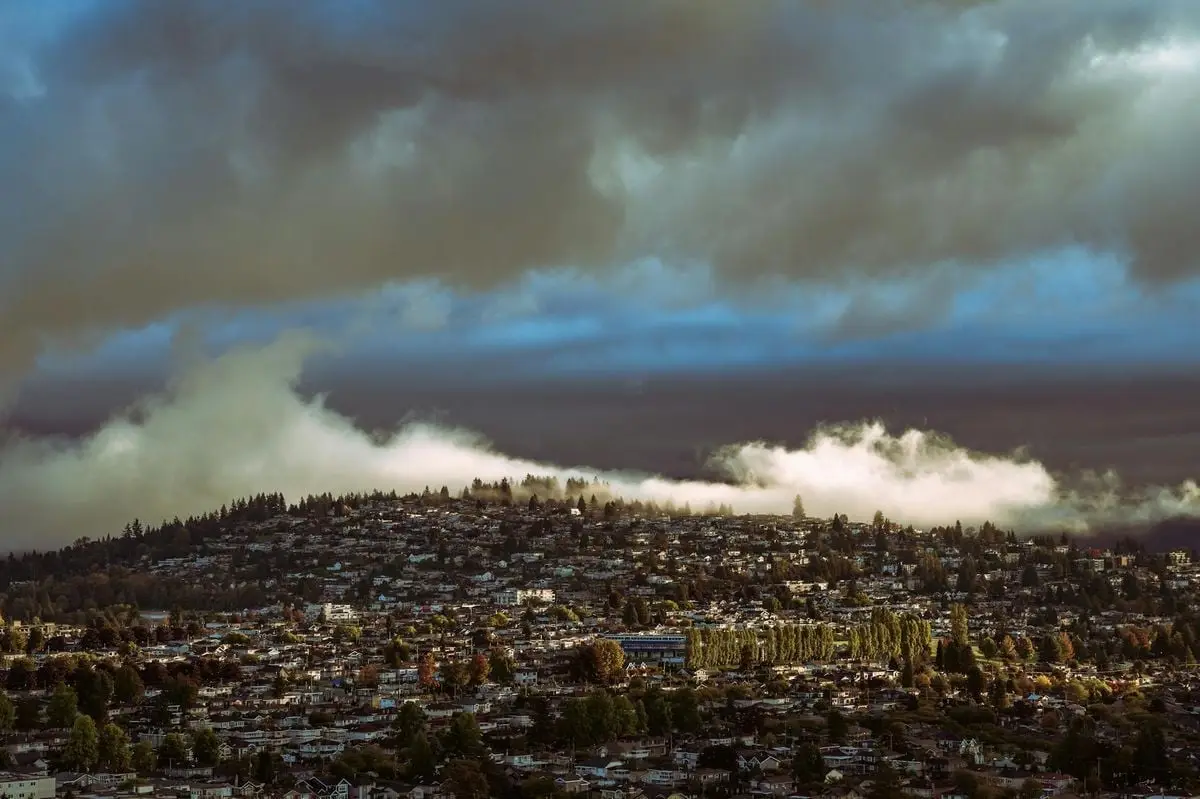 Aerial view of a cityscape under dramatic skies and clouds, showcasing a unique blend of urban and natural elements.