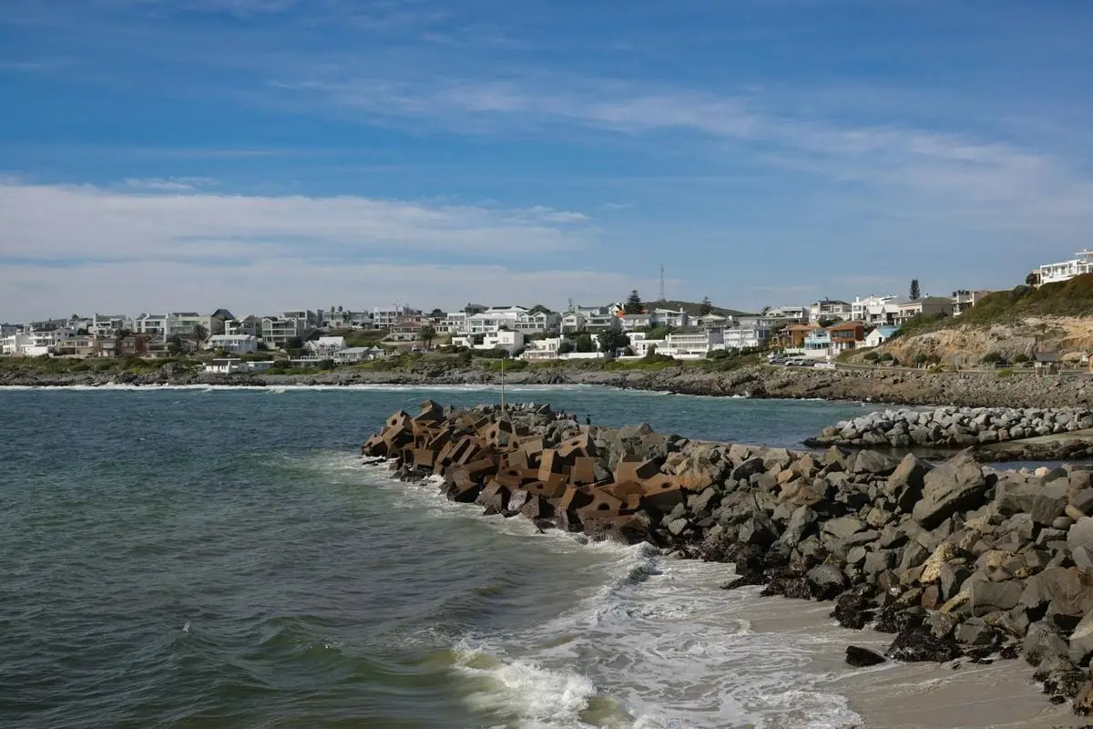 Scenic coastal view with rocky shoreline and white homes in South Africa.