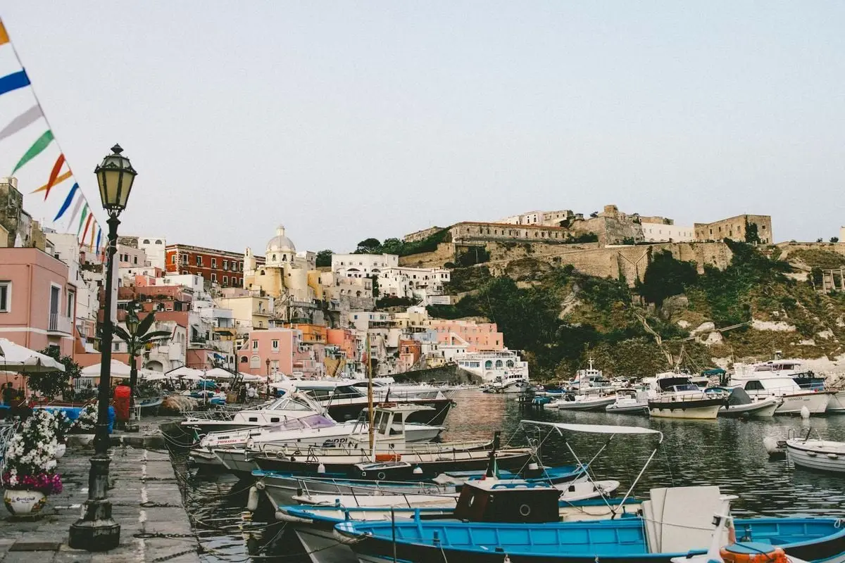 Explore the colorful buildings and moored boats in Procida's charming harbor.