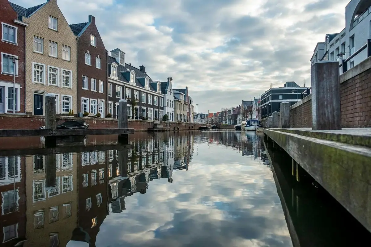 Picturesque canal lined with historic buildings reflecting in the water in a European old town setting.