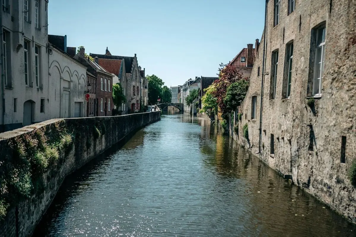Explore the picturesque canals and medieval architecture of Bruges, Belgium, on a sunny day.