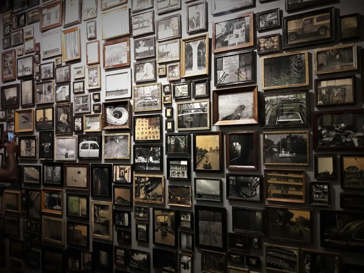 A diverse collection of framed photographs displayed on a gallery wall in Kochi, India.