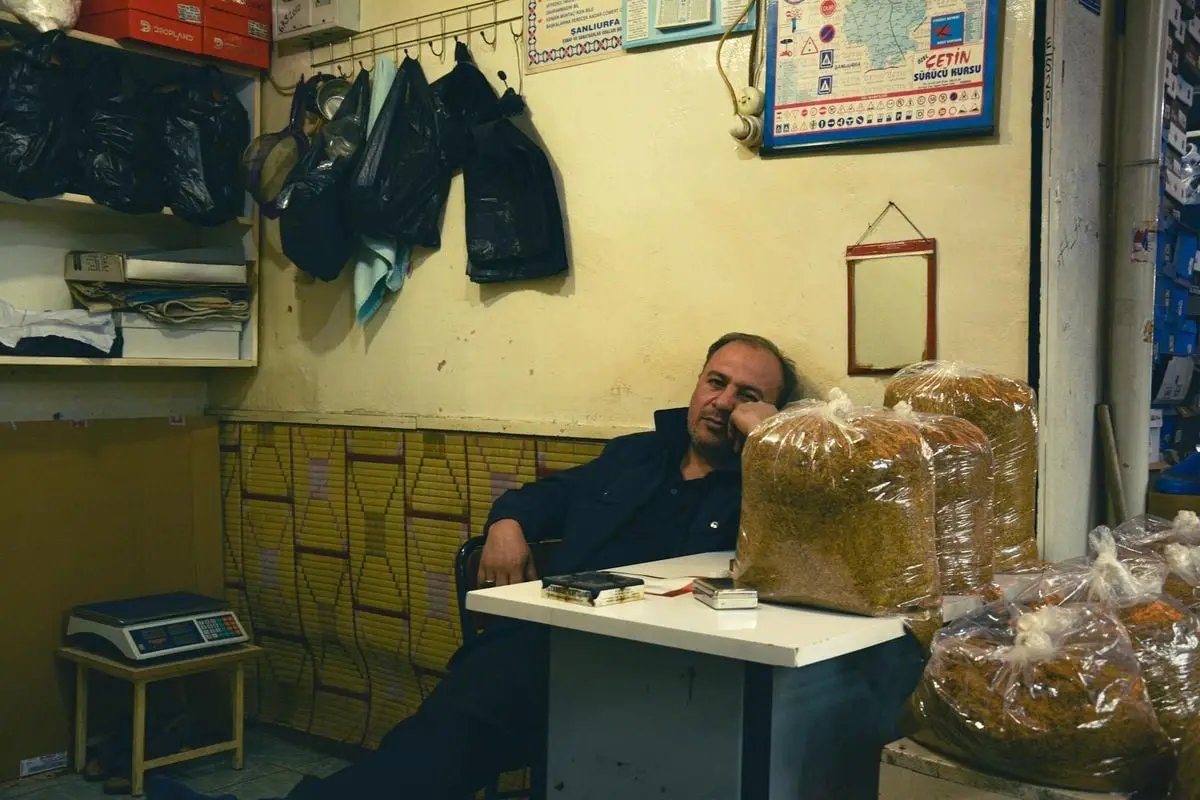 Shopkeeper relaxing at a small spice shop filled with bagged spices and goods.