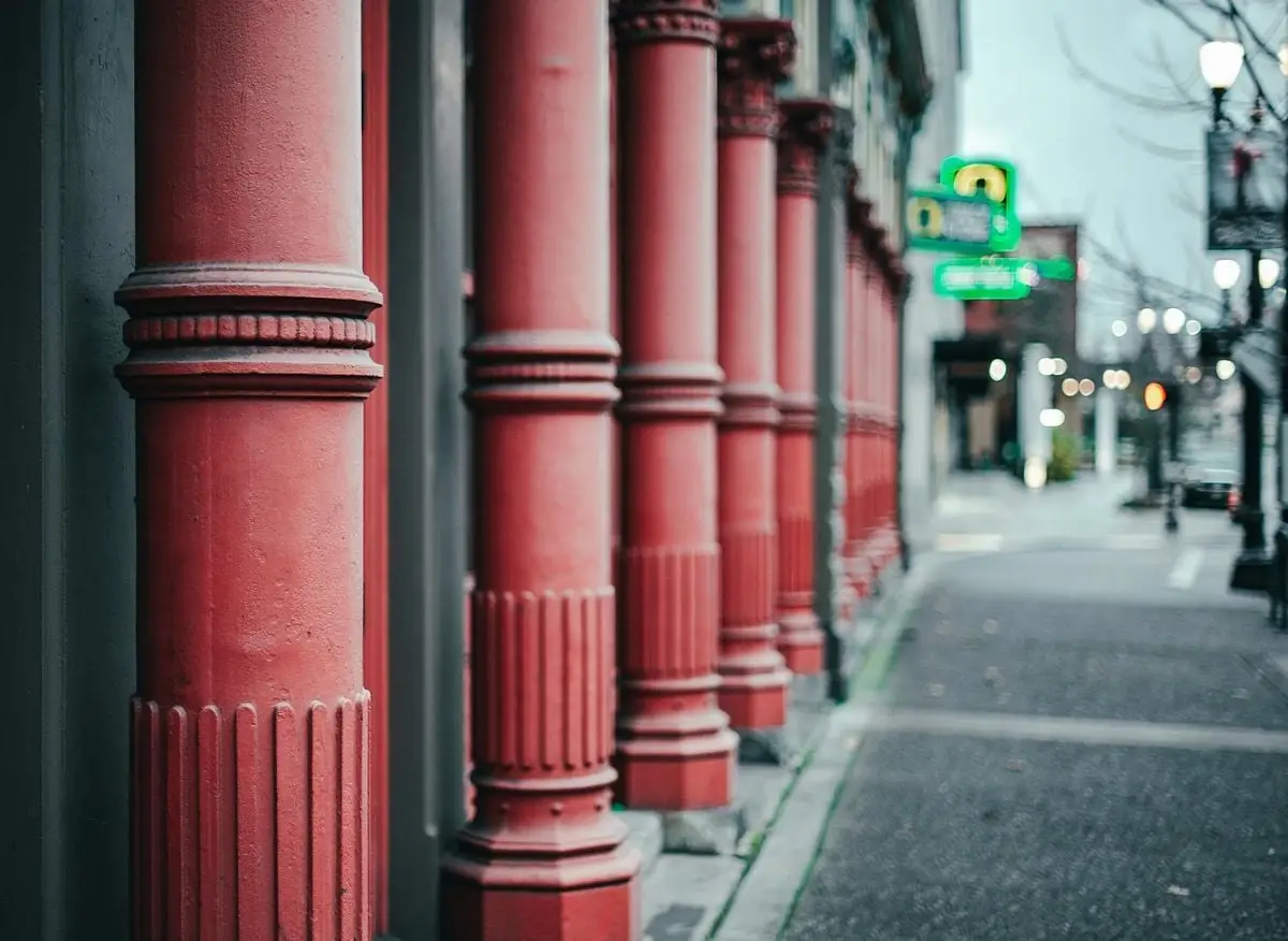 Blurred city street view with decorative red columns and urban architecture.