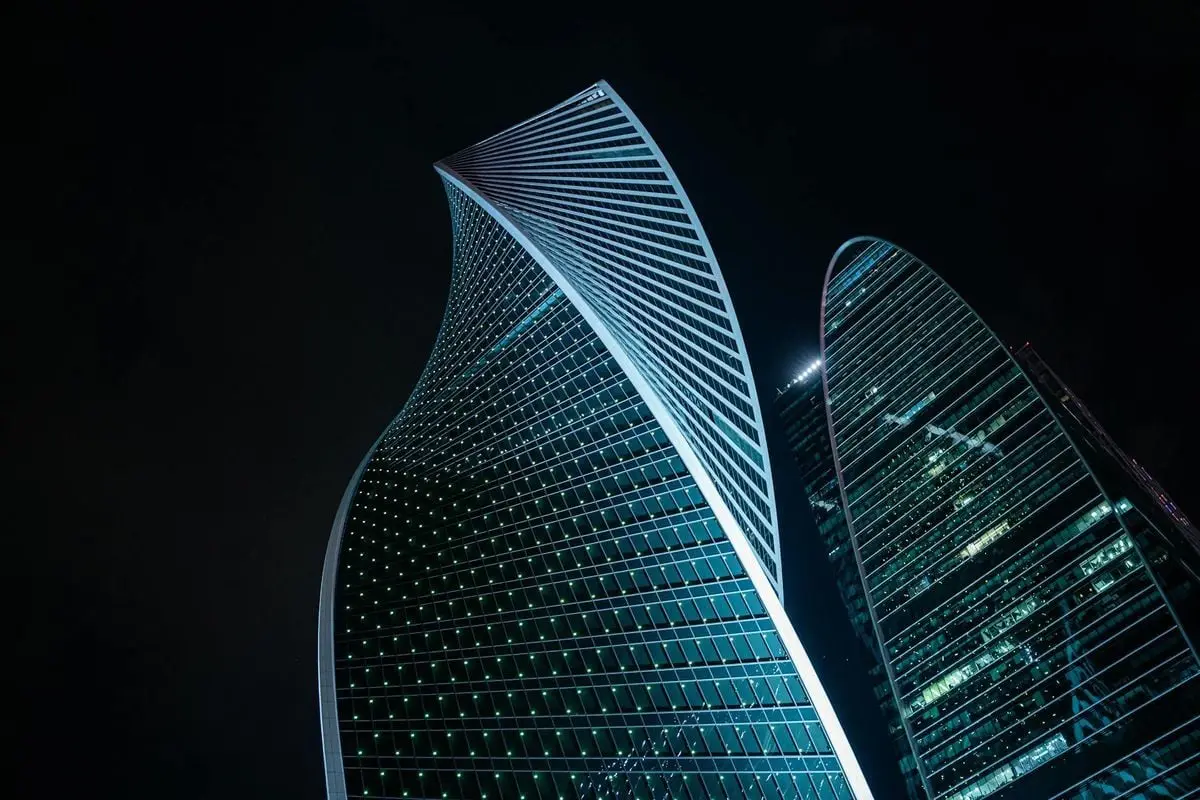 Striking low-angle view of modern skyscrapers illuminated against the night sky.