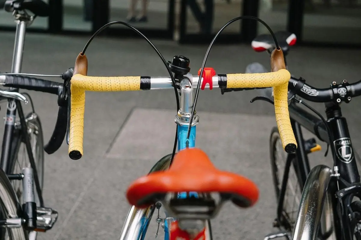 Vibrant yellow handlebars of a parked road bicycle in an urban setting.