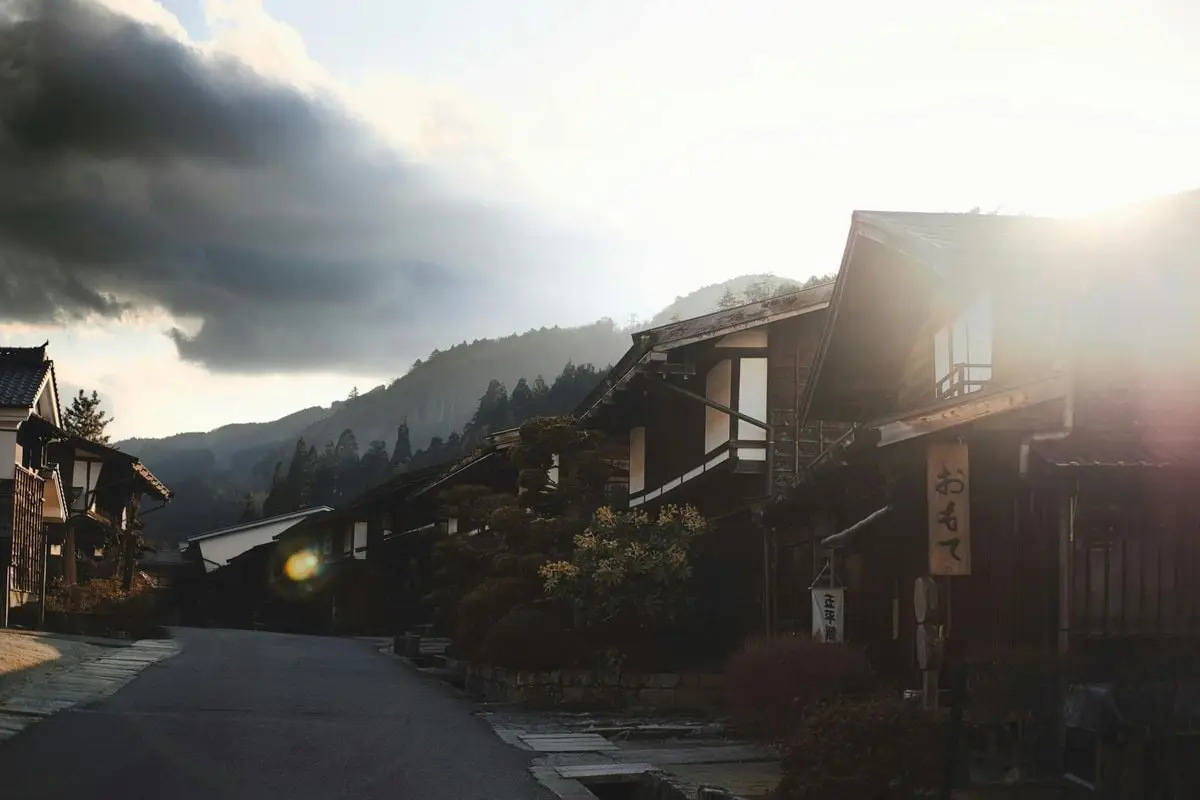 Charming village scene in Japan with traditional homes and mountains at sunrise.