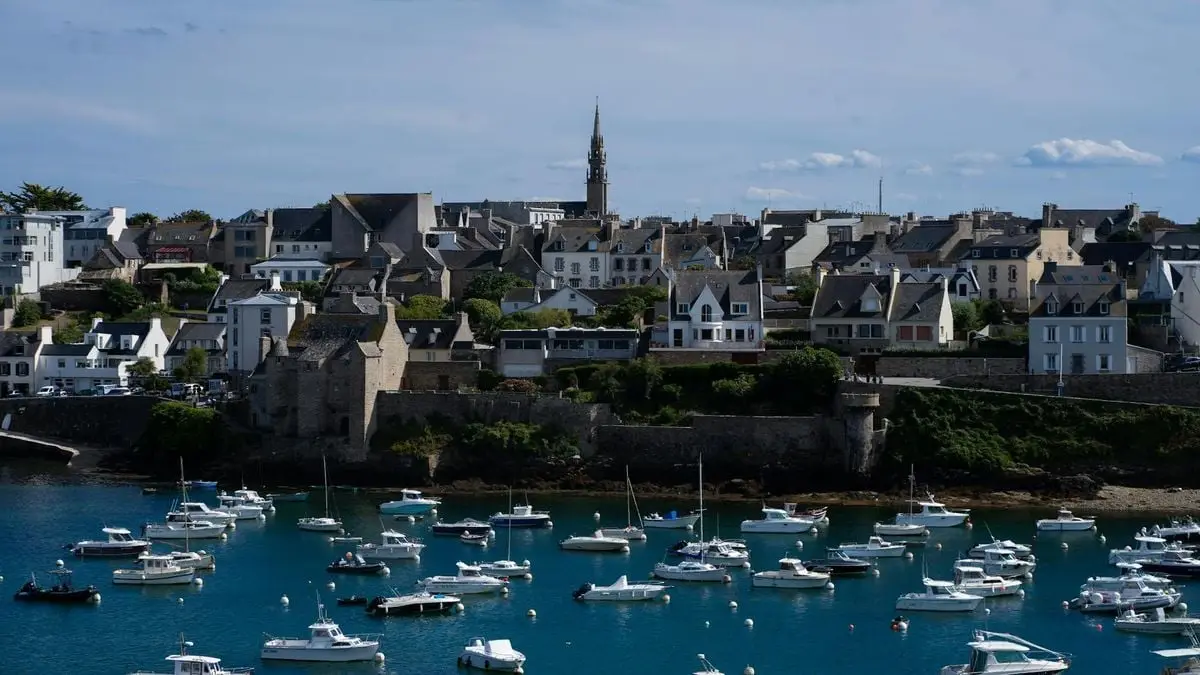 Picturesque French harbor with historic architecture and sailboats.