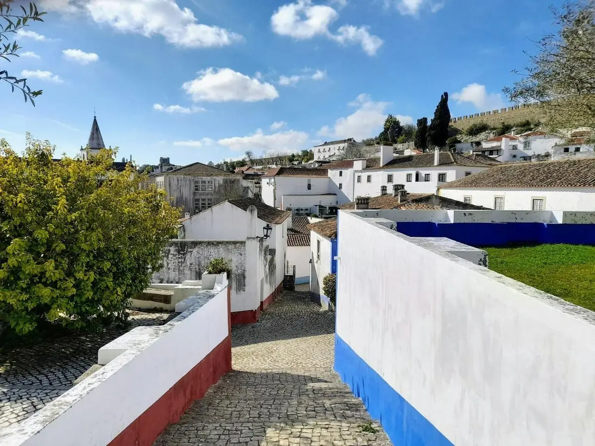Explore the picturesque streets of Óbidos, Portugal, featuring colorful architecture and a bright spring day.