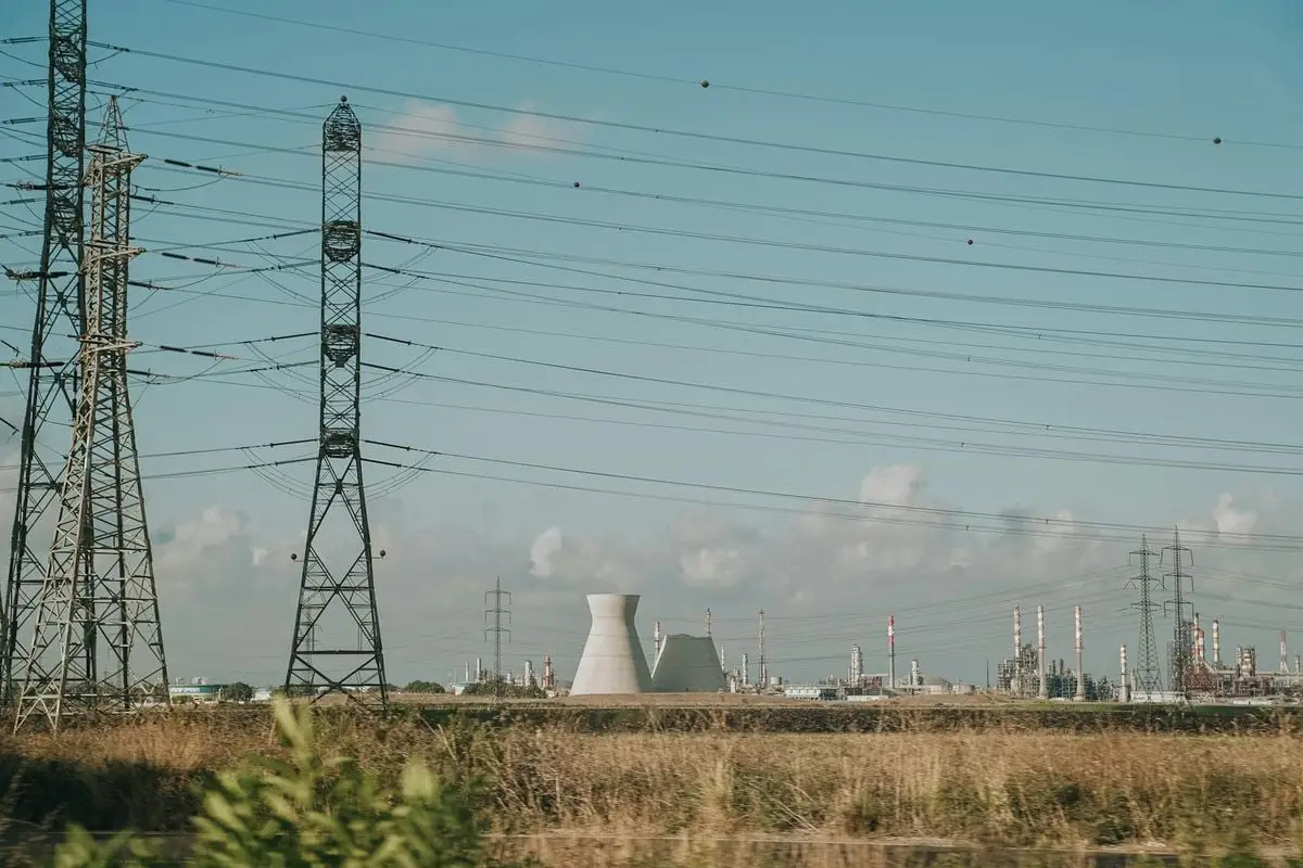 Scenic view of high voltage towers and power plant against a clear sky over dry grassland.