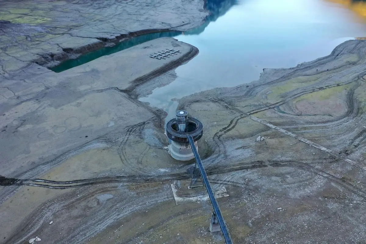 Stunning aerial view of a reservoir structure amidst a dry lake in Glarus, Switzerland.
