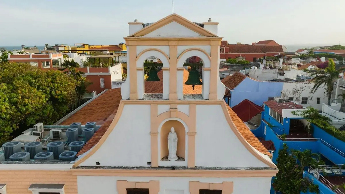 Aerial view of a historic church bell tower amidst colorful rooftops in Cartagena, Colombia.