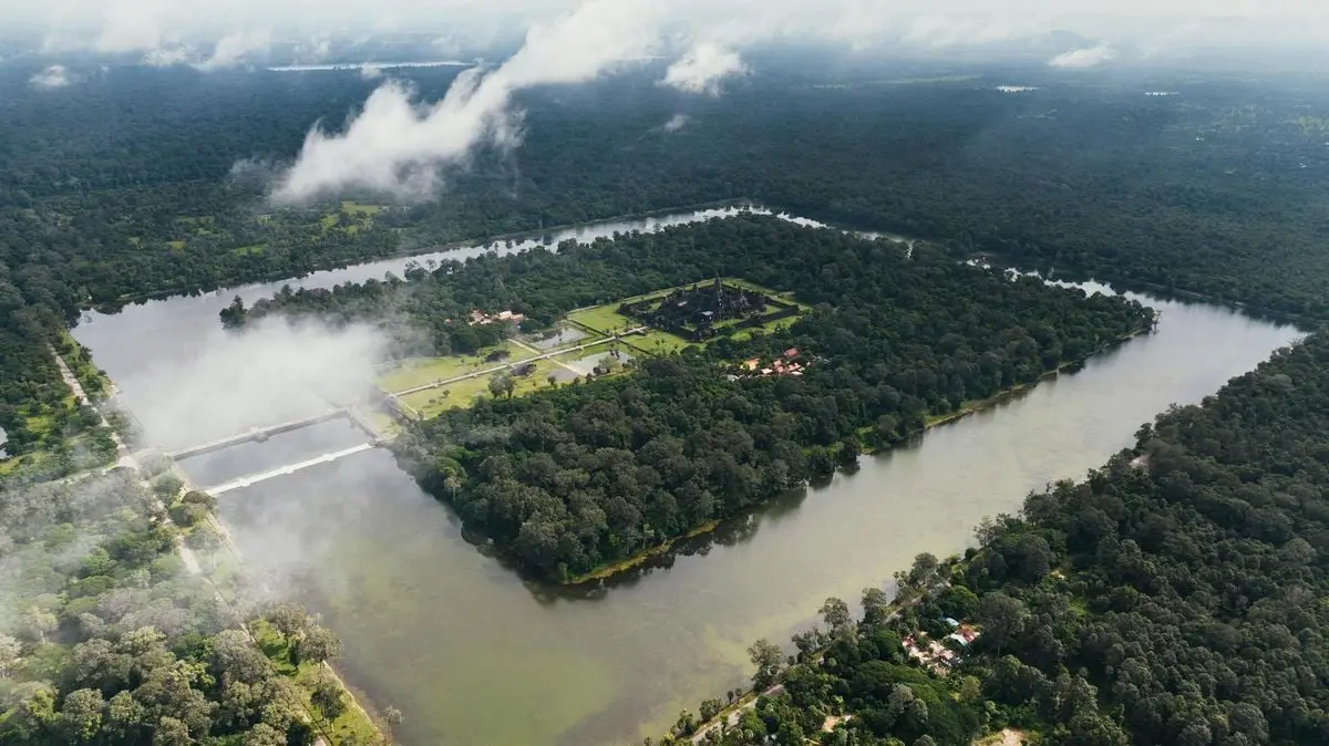 Explore the breathtaking aerial view of Angkor Wat with its lush surroundings and man-made reservoirs in Cambodia.