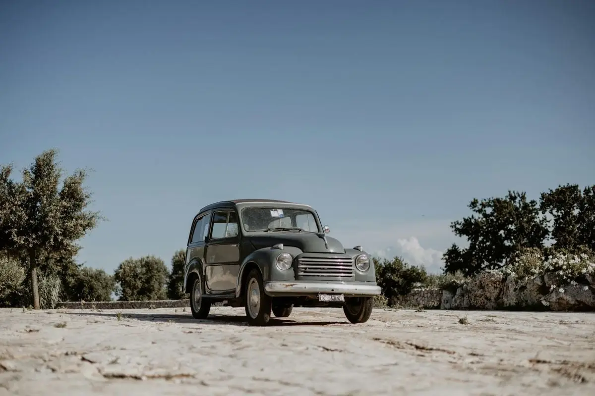Classic Fiat 500 Topolino parked outdoors in Ostuni, Apulia, Italy under a clear, sunlit sky.