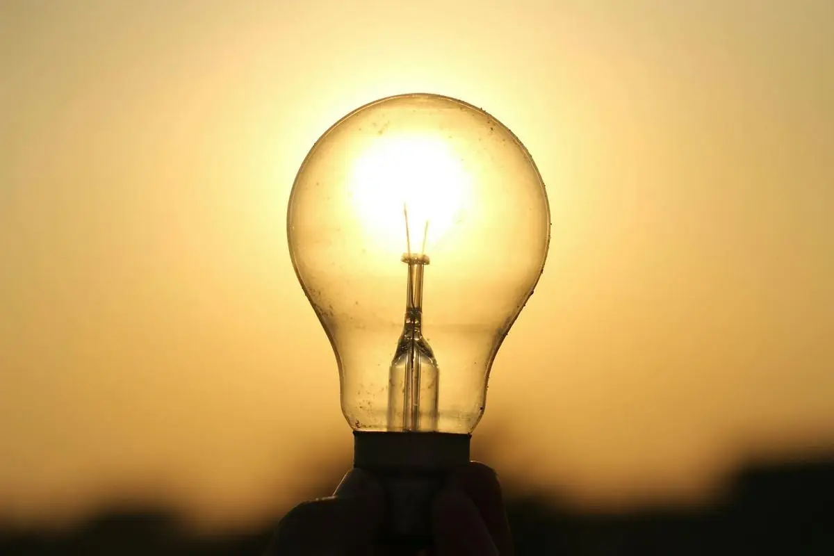 A light bulb held against a golden sunset in Lahore, symbolizing energy and innovation.