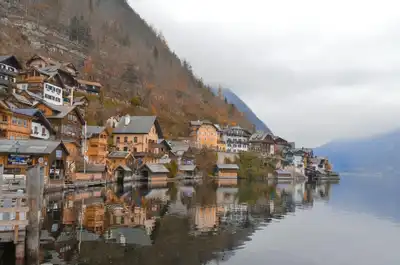 Breathtaking autumn scenery of Hallstatt, Austria, overlooking the lake and traditional architecture against misty mountains.