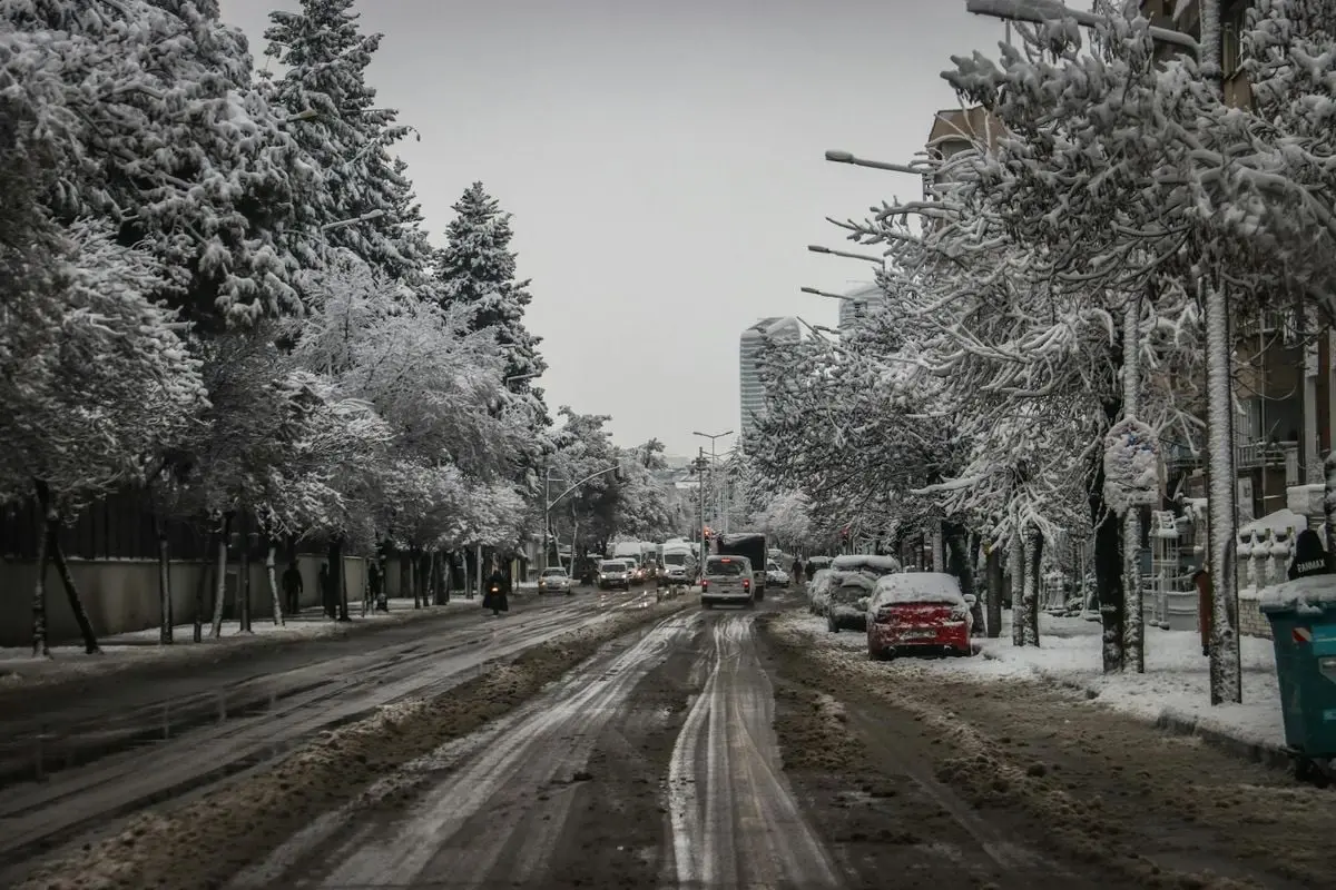 Snow-covered street with traffic and trees in Gaziantep during winter.