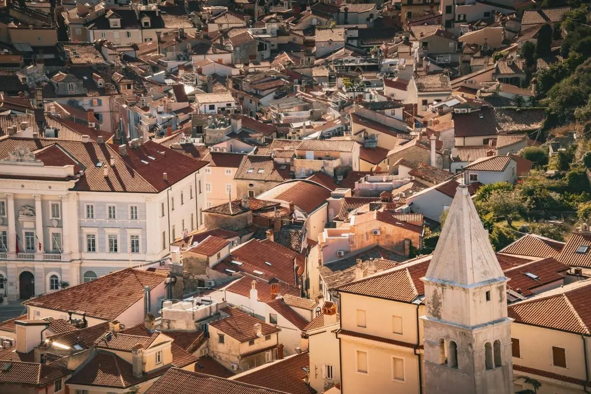 Charming aerial view of a historic European town with red-tiled rooftops in warm sunlight.