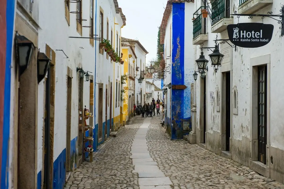 Cobblestone street with colorful houses in a historic Portuguese town.