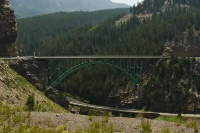 A beautiful view of the Red Cliff Bridge surrounded by lush green mountains in Vail, Colorado.