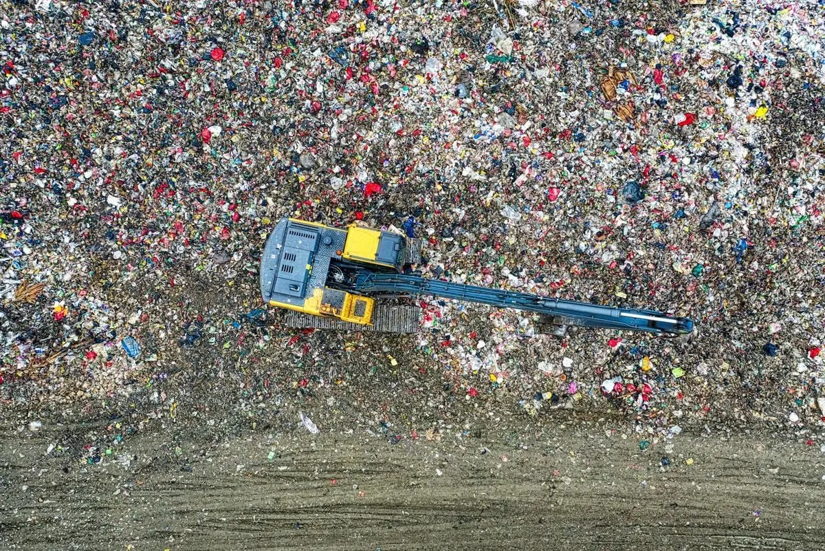 Aerial shot of an excavator working at a large waste disposal site in Banten, Indonesia.